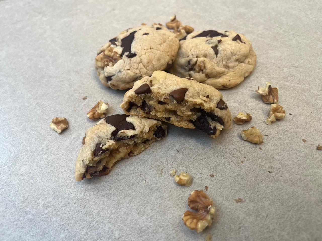 A cookie split in half showing the rich layers of walnut, dark chocolate, and milk chocolate inside it. No cookies in Dubai come close to this marvel